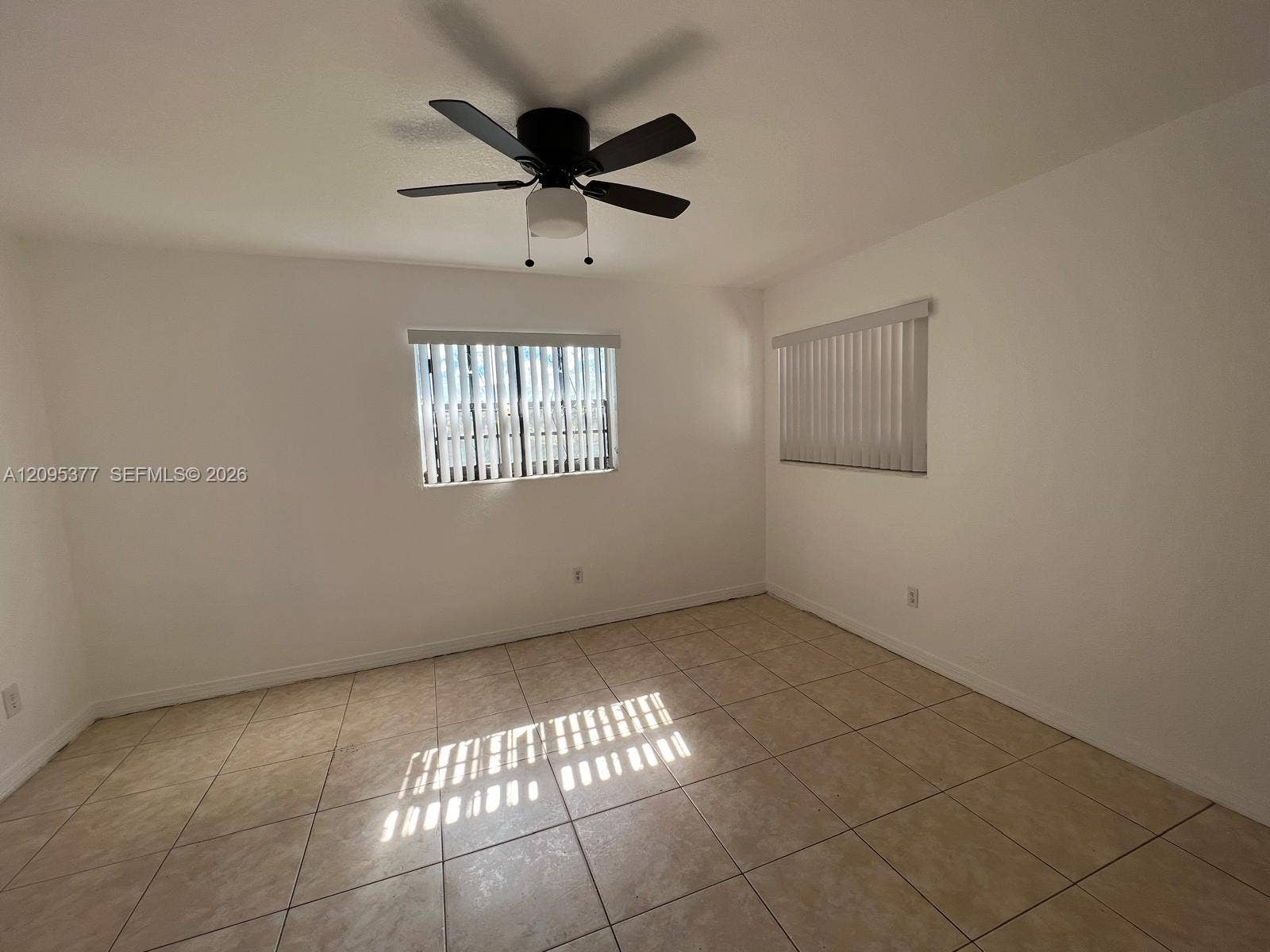 570 NW 41st Street, Miami, FL 33127 Neutral wall tones, ceramic tile flooring, matte black ceiling fan with integrated lighting, and vertical window blinds