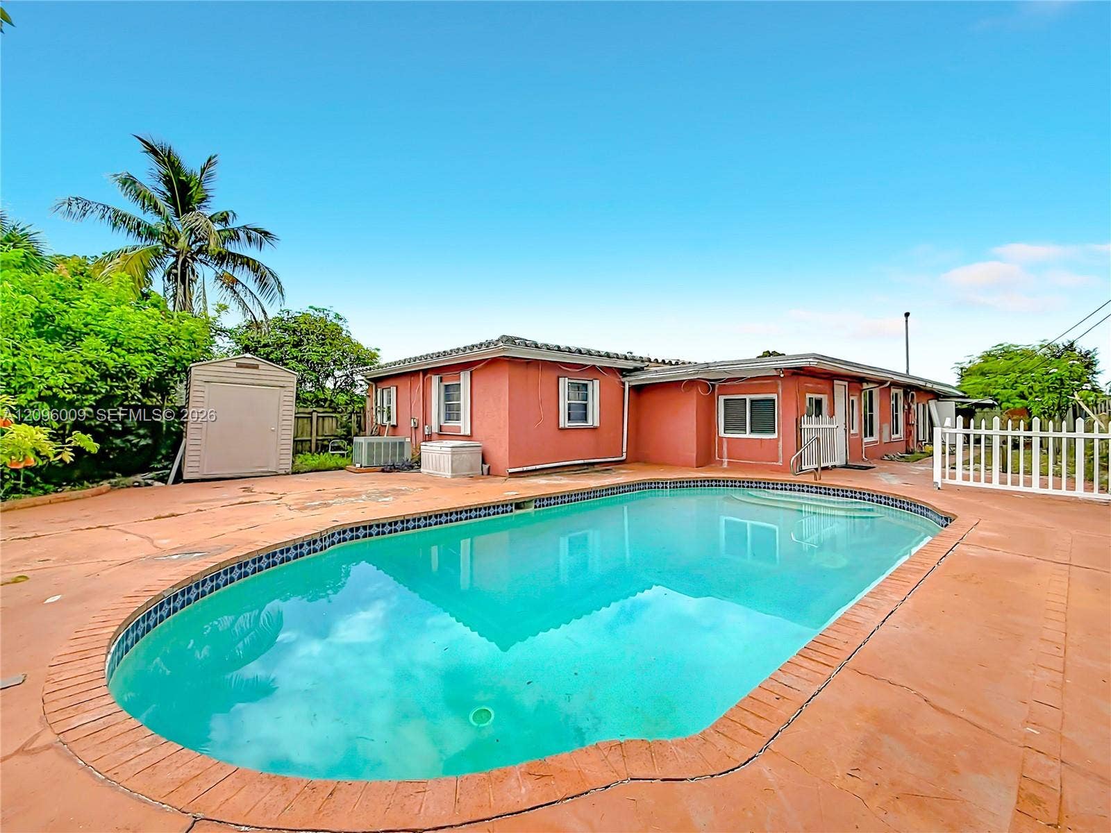 1191 Alabama Avenue, Fort Lauderdale, FL 33312 In-ground swimming pool with tile trim, expansive concrete patio, stucco exterior finish, and detached outdoor storage structure