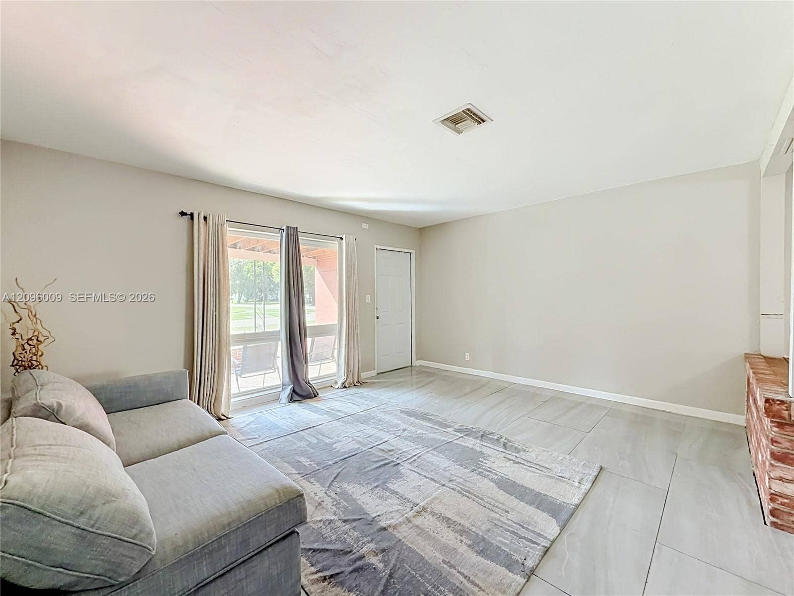 1191 Alabama Avenue, Fort Lauderdale, FL 33312 Neutral-toned interior featuring large-format tile flooring, a red brick fireplace surround, and floor-to-ceiling glass sliding doors