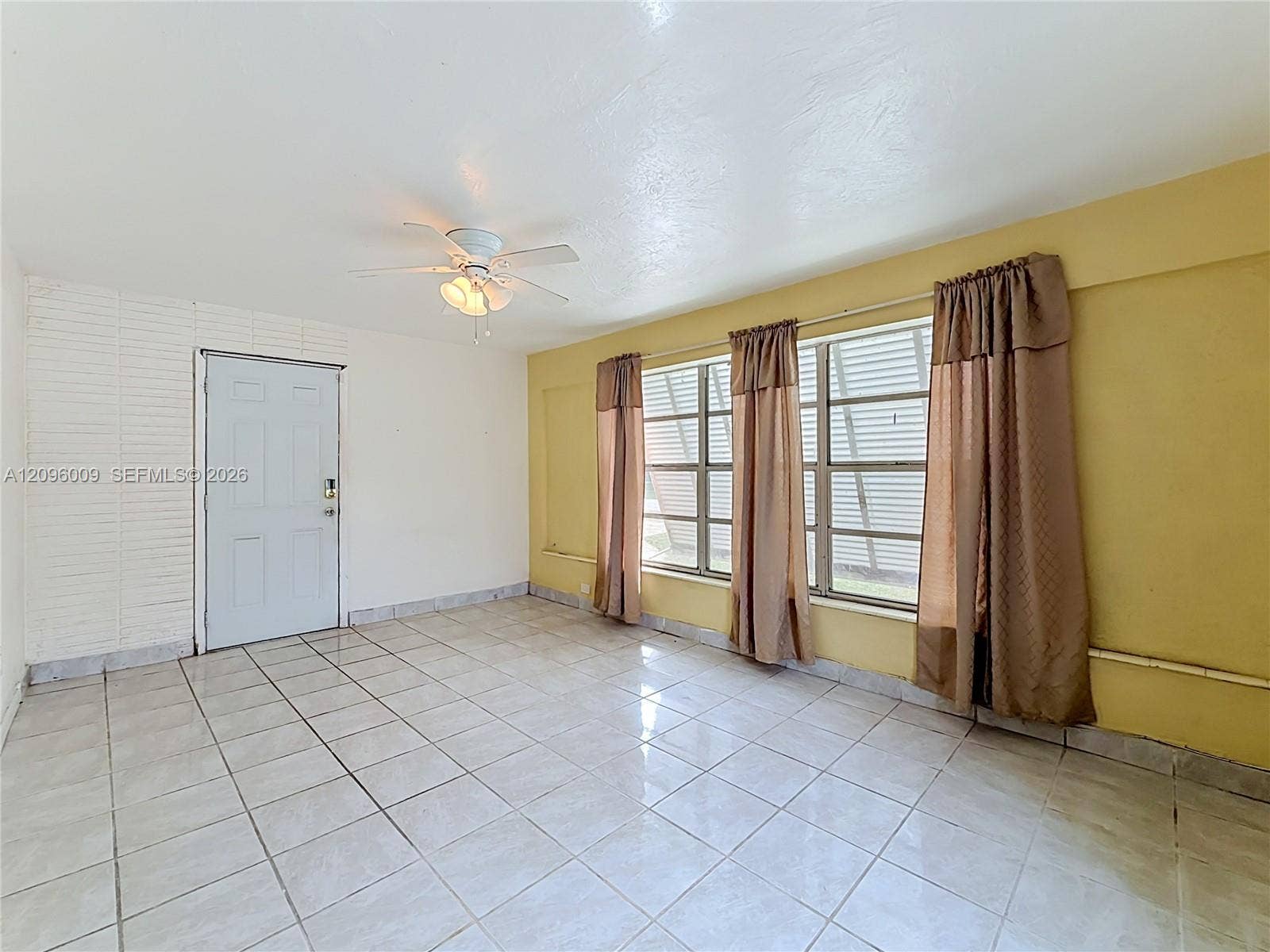 1191 Alabama Avenue, Fort Lauderdale, FL 33312 Interior space featuring ceramic tile flooring, a painted brick accent wall, and a central ceiling fan with integrated lighting
