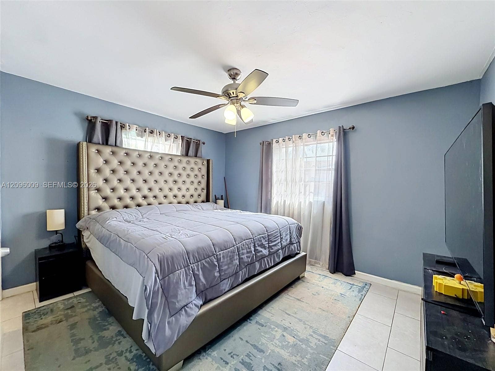 1191 Alabama Avenue, Fort Lauderdale, FL 33312 Light-filled room featuring large windows with neutral-toned treatments, tile flooring, and a ceiling-mounted light fixture with a central fan