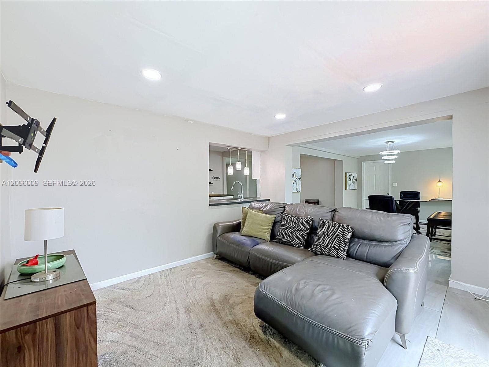 1191 Alabama Avenue, Fort Lauderdale, FL 33312 Living area featuring neutral-toned walls, recessed lighting, and a pass-through window to the kitchen