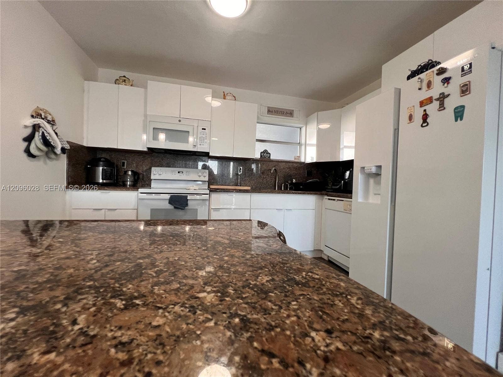 6300 SW 138th Court, #405, Miami, FL 33183 Kitchen featuring white cabinetry, stone-finish countertops, an island, and integrated white appliances
