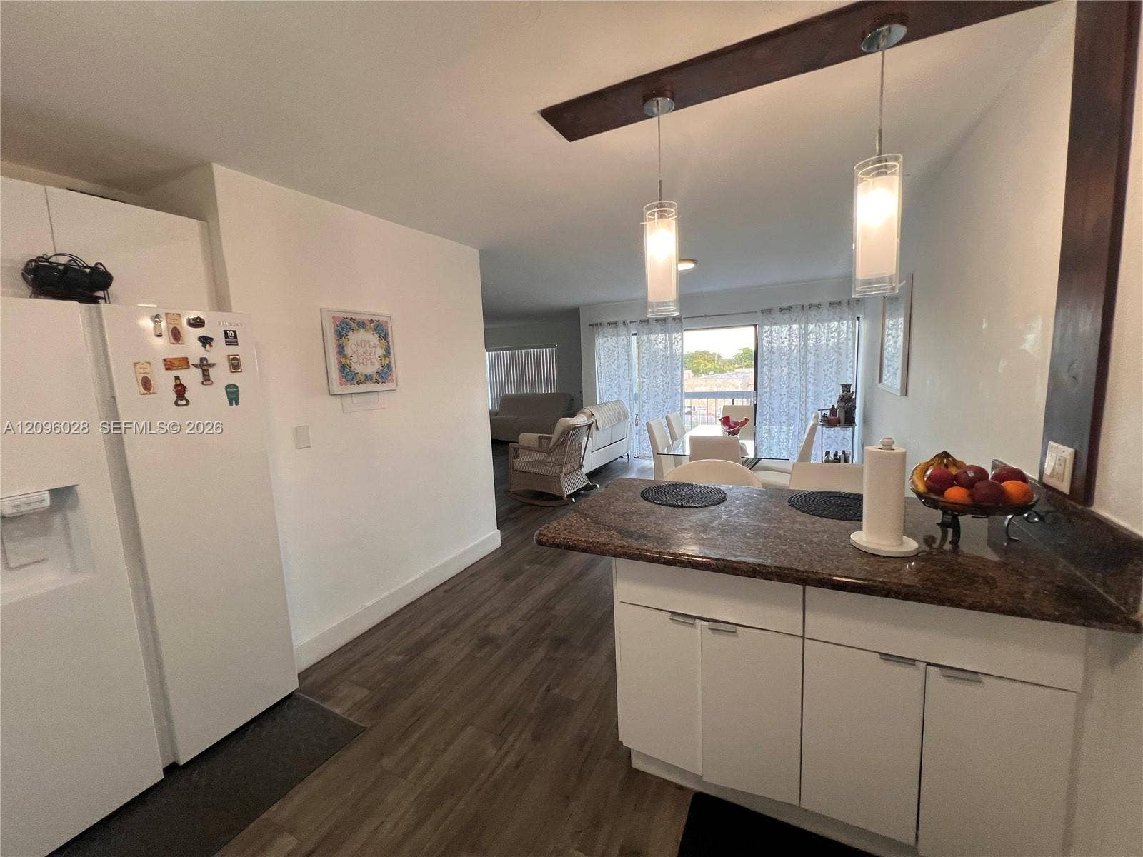 6300 SW 138th Court, #405, Miami, FL 33183 Kitchen featuring a breakfast bar with stone-finish countertop, white cabinetry, wood-finish flooring, and dual hanging pendant lights