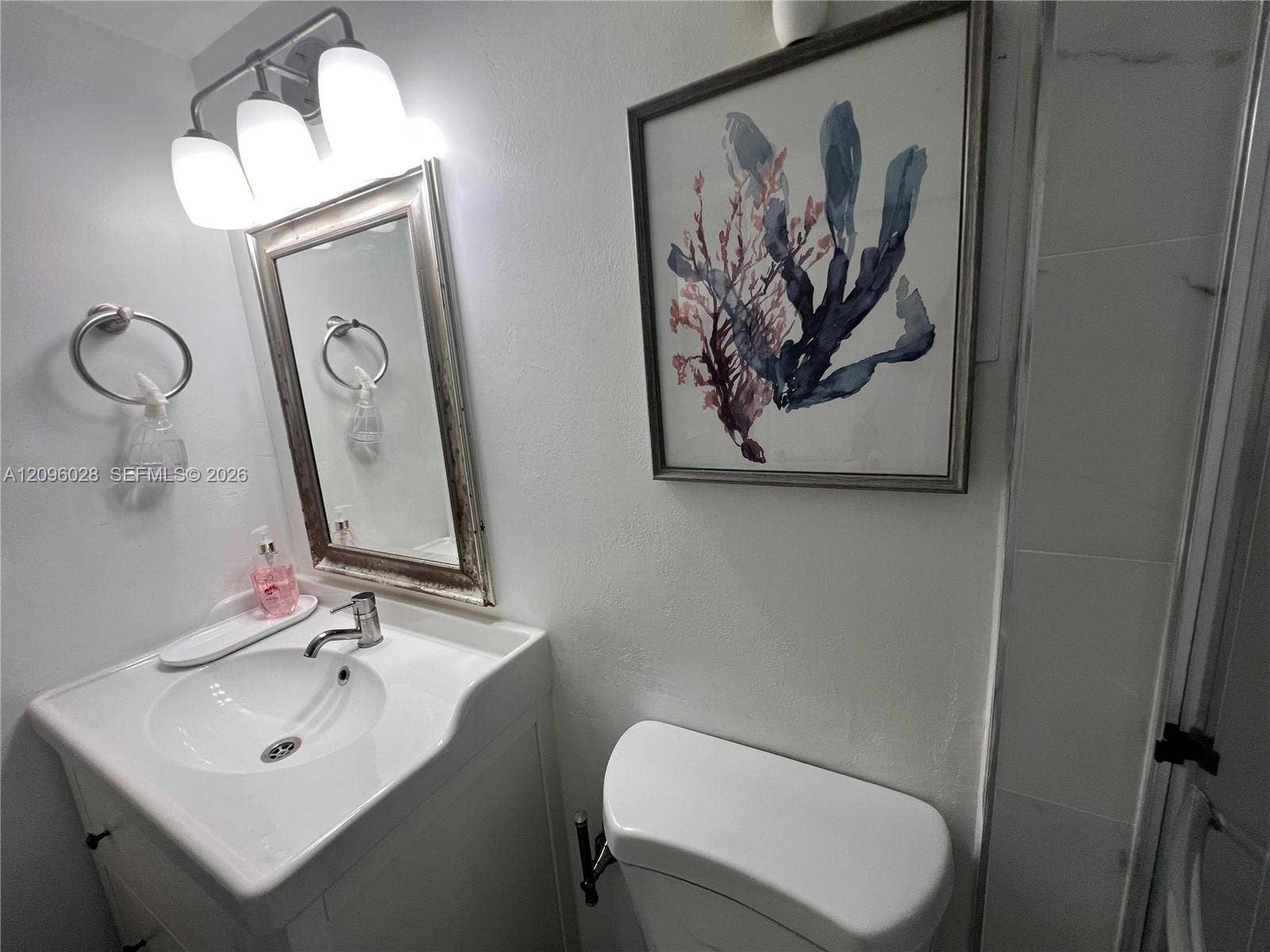 6300 SW 138th Court, #405, Miami, FL 33183 Vanity featuring a white integrated sink, polished metal faucet, three-light overhead fixture, and rectangular mirror