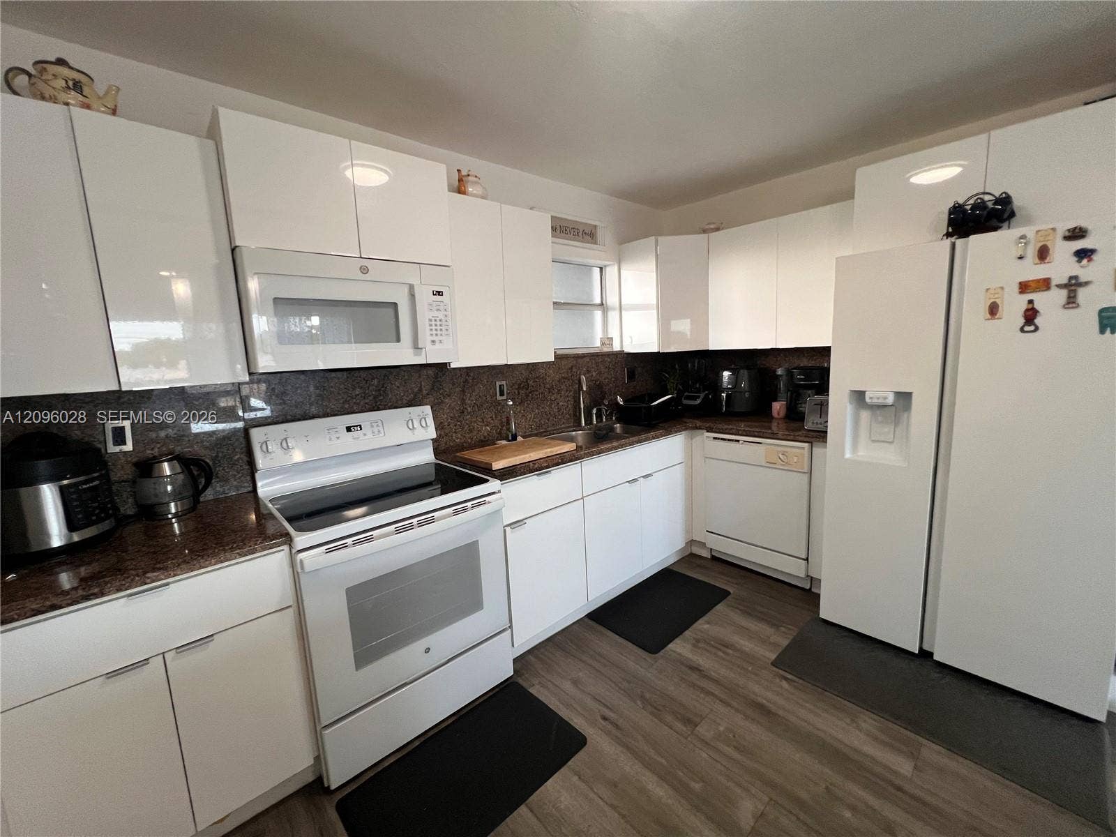 6300 SW 138th Court, #405, Miami, FL 33183 Kitchen featuring high-gloss white cabinetry, stone countertops, wood-finish flooring, and white appliances