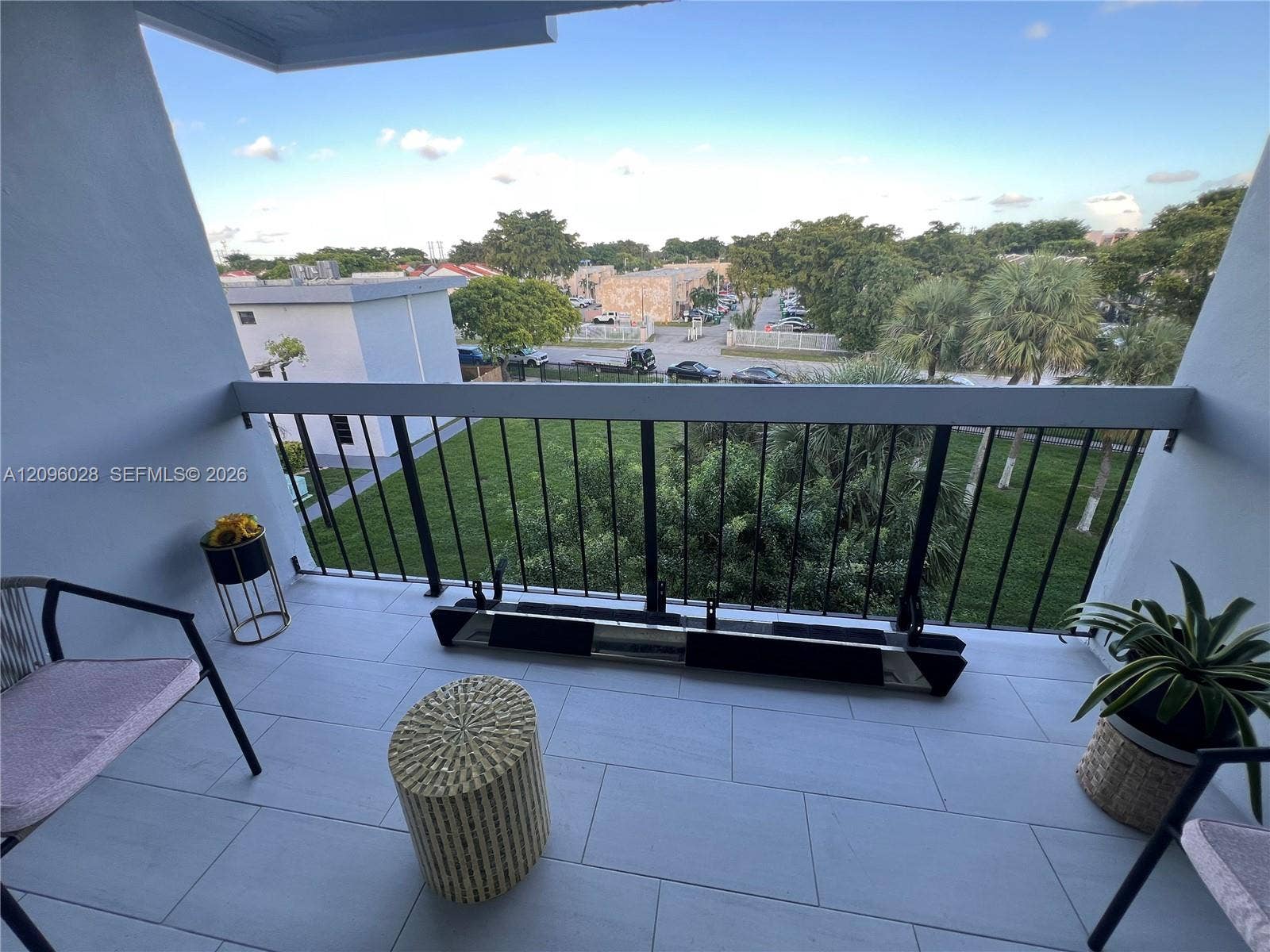 6300 SW 138th Court, #405, Miami, FL 33183 Covered balcony featuring large-format grey floor tiling, a black metal railing, and an open outdoor space