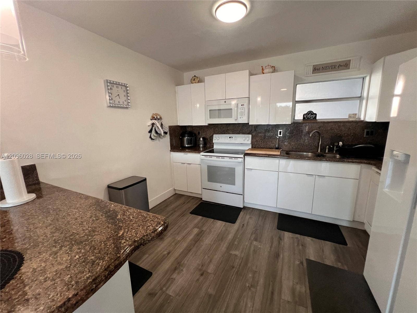 6300 SW 138th Court, #405, Miami, FL 33183 Kitchen featuring high-gloss white cabinetry, stone-finish countertops, wood-finish flooring, and a stainless steel sink with an integrated faucet