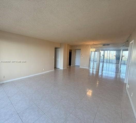 20355 NE 34th Court, #1925, Aventura, FL 33180 Open-concept interior featuring oversized tile flooring, full-length glass sliding doors, and a crystal-style chandelier