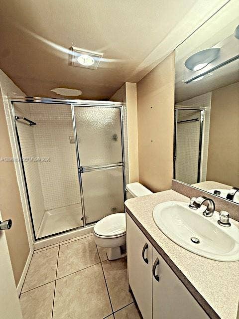 20355 NE 34th Court, #1925, Aventura, FL 33180 Bathroom featuring a walk-in shower with glass sliding doors and tile surround, vanity with an integrated sink and chrome faucet, large wall-mounted mirror, and tile flooring