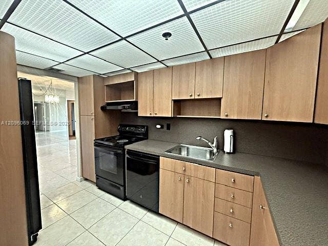 20355 NE 34th Court, #1925, Aventura, FL 33180 Kitchen featuring light wood-finish cabinetry, solid-surface countertops, integrated stainless steel sink with a swivel faucet, and full-size black appliances including an oven range and dishwasher