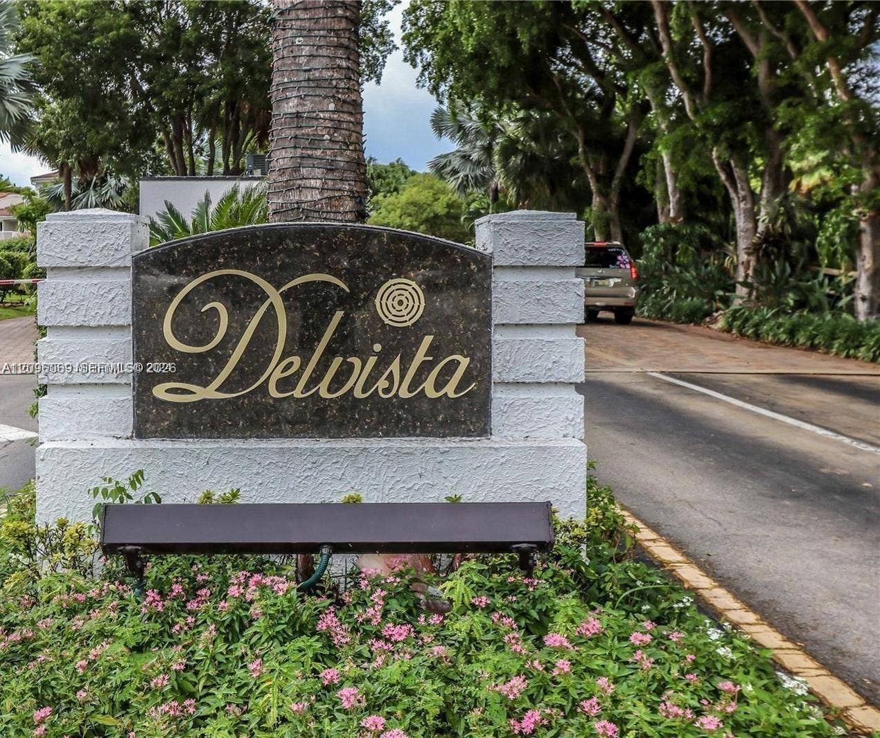 20355 NE 34th Court, #1925, Aventura, FL 33180 Community signage featuring a dark stone plaque with gold lettering, set within a textured white masonry monument base, surrounded by manicured landscaping and mature trees