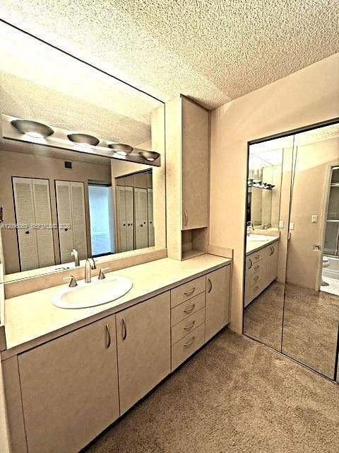 20355 NE 34th Court, #1925, Aventura, FL 33180 Bathroom featuring a vanity with integrated cabinetry, a recessed oval sink, a wall-to-wall mirror, overhead vanity lighting, and floor-to-ceiling mirrored closet doors