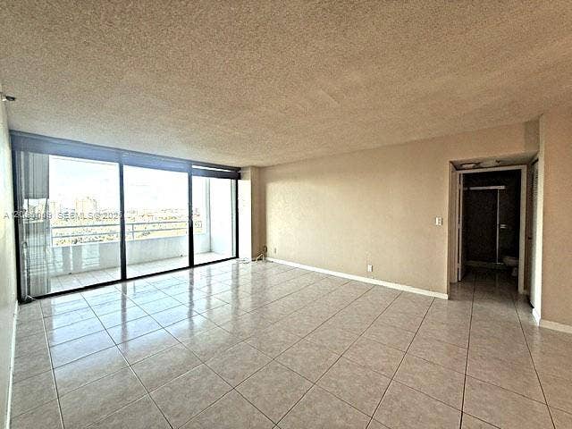 20355 NE 34th Court, #1925, Aventura, FL 33180 Open living area featuring large-format ceramic tile flooring, neutral wall finishes, and floor-to-ceiling sliding glass doors opening to a balcony