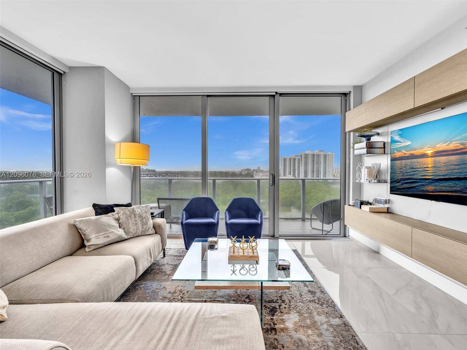 16385 Biscayne Boulevard, #1101, North Miami Beach, FL 33160 Floor-to-ceiling glass sliding doors, polished tile flooring, built-in wall-mounted cabinetry with wood-finish paneling, and an expansive balcony