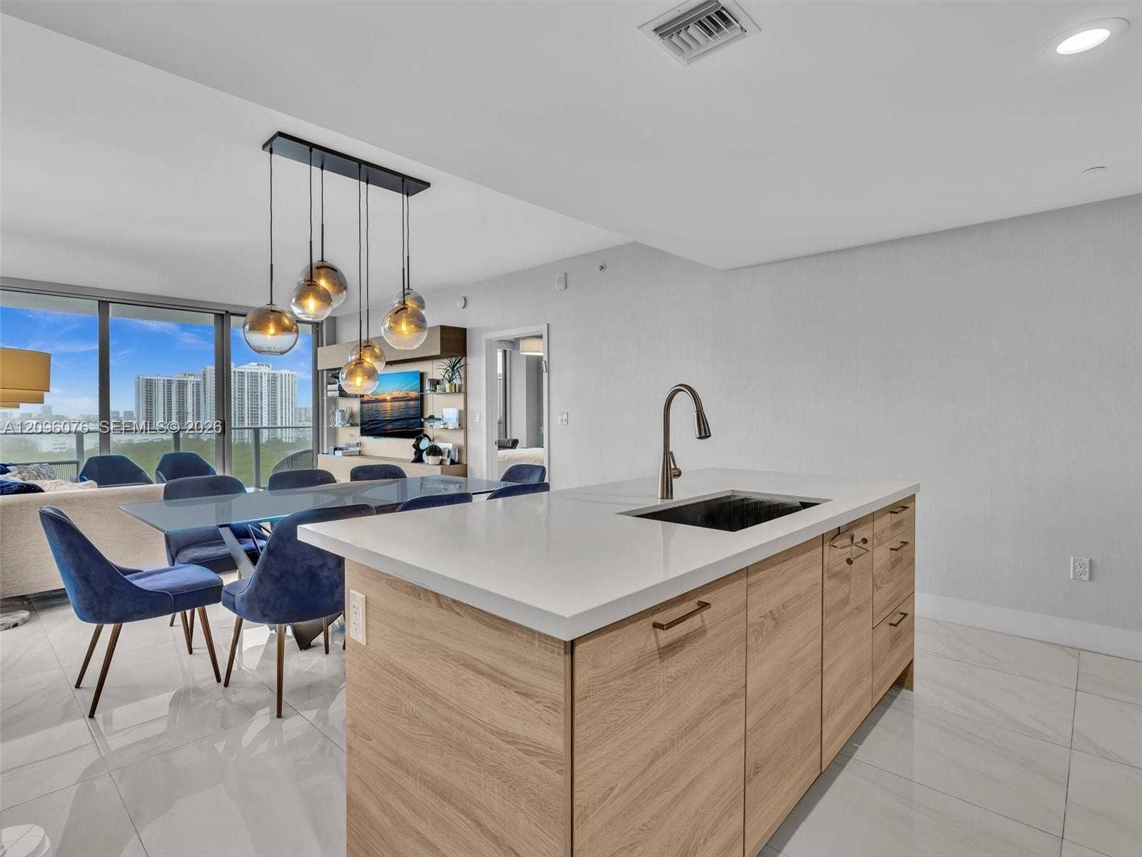 16385 Biscayne Boulevard, #1101, North Miami Beach, FL 33160 Kitchen island with wood-finish cabinetry, white countertop, and under-mount sink featuring a gooseneck faucet