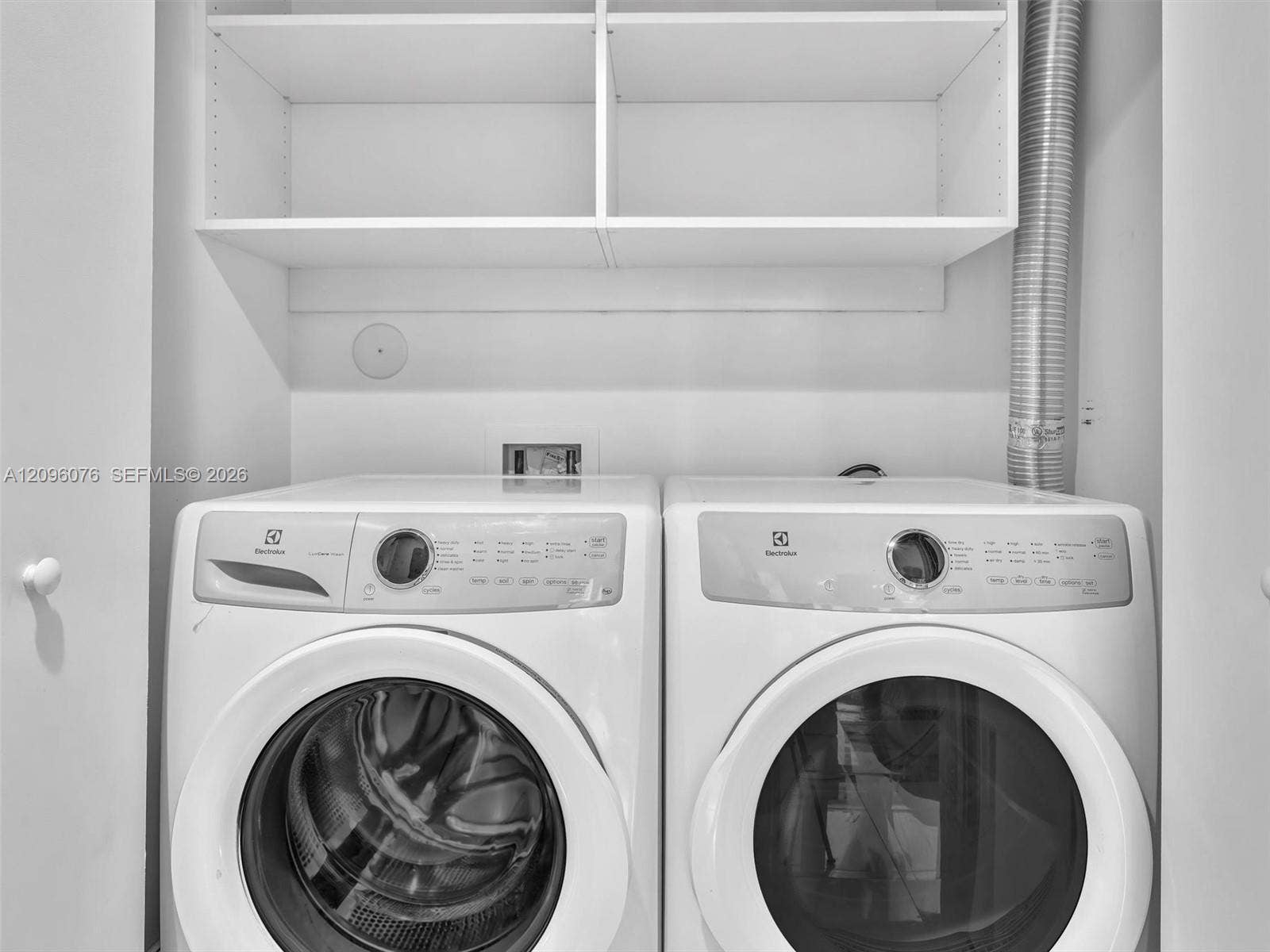 16385 Biscayne Boulevard, #1101, North Miami Beach, FL 33160 Laundry space featuring stacked white custom shelving and side-by-side front-loading appliances