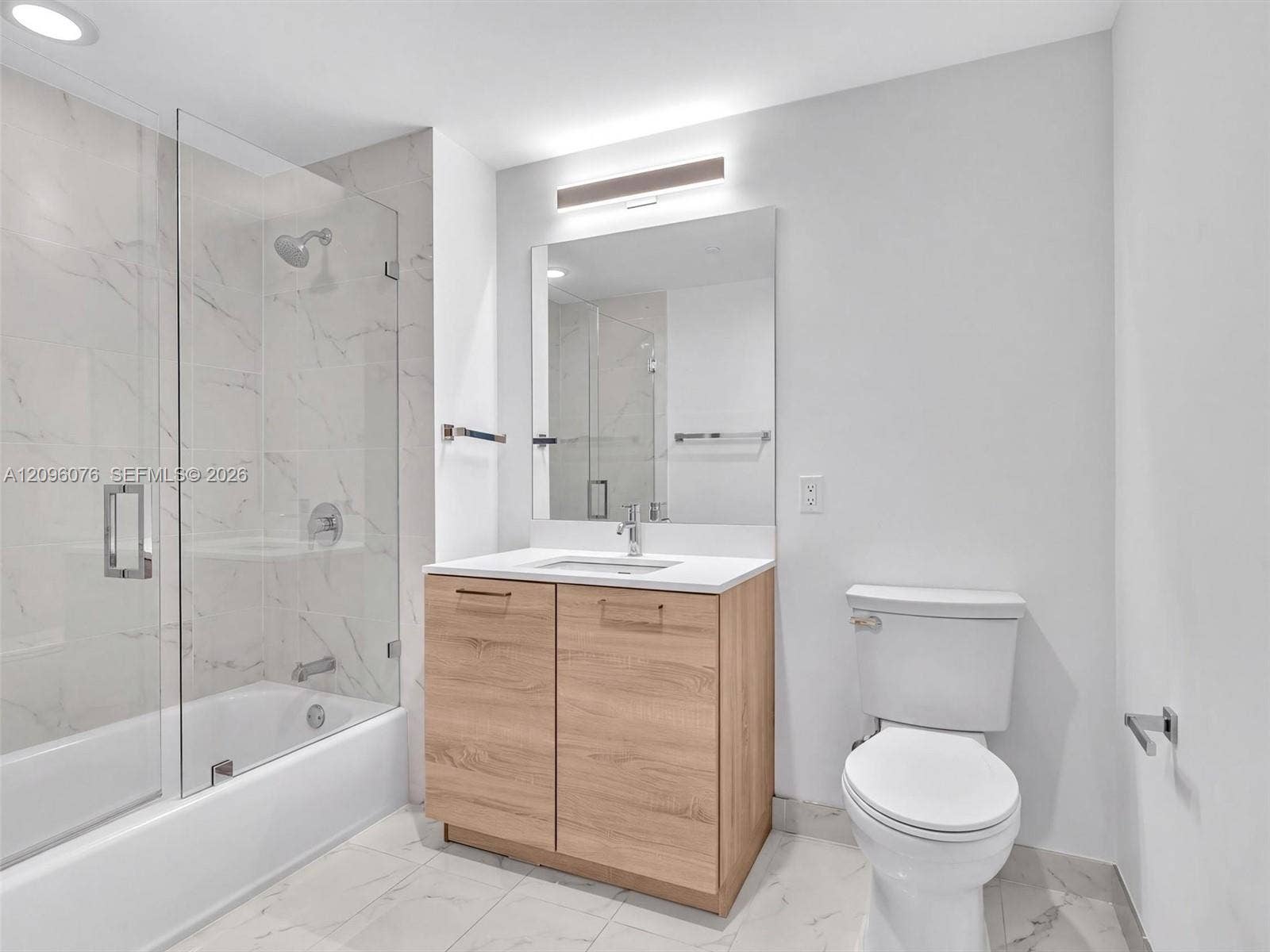 16385 Biscayne Boulevard, #1101, North Miami Beach, FL 33160 Bathroom featuring a wood-finish vanity with a stone countertop, a glass-enclosed shower and tub combination with tile surround, and large-format tile flooring