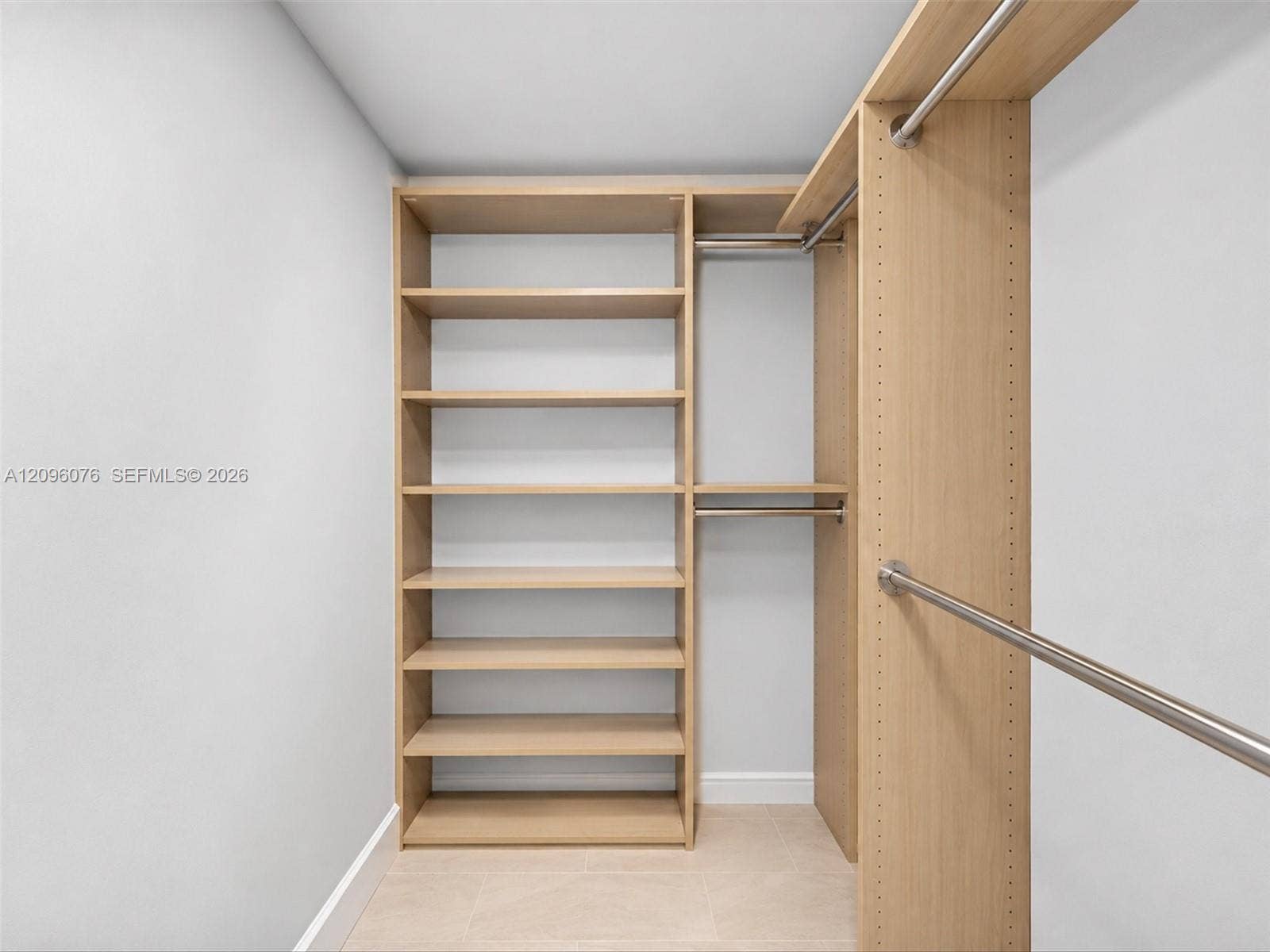 16385 Biscayne Boulevard, #1101, North Miami Beach, FL 33160 Custom built-in storage featuring light wood-finish shelving, integrated metallic hanging rods, and adjustable hardware