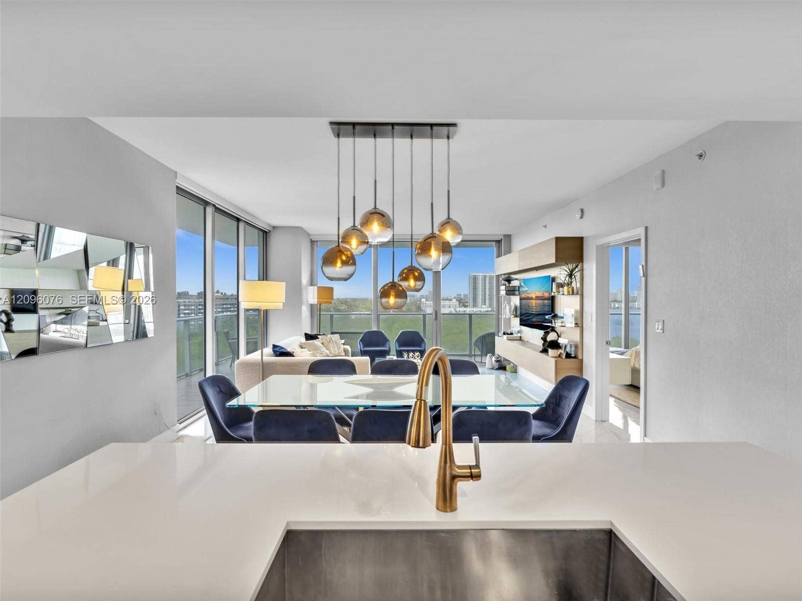 16385 Biscayne Boulevard, #1101, North Miami Beach, FL 33160 Solid surface countertops, under-mount stainless steel sink, bronze-tone faucet, multi-light pendant fixture with spherical glass shades, and floor-to-ceiling glass panel walls