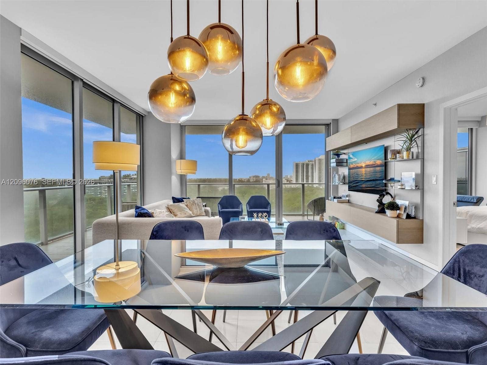 16385 Biscayne Boulevard, #1101, North Miami Beach, FL 33160 Multi-light pendant fixture with metallic-finish glass globes, floor-to-ceiling glass panel walls, and built-in wall-mounted cabinetry with a neutral wood-finish