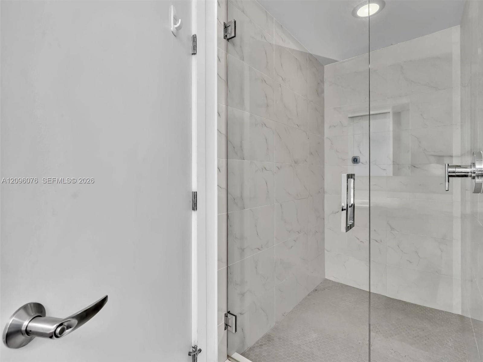 16385 Biscayne Boulevard, #1101, North Miami Beach, FL 33160 Walk-in shower featuring large-format stone-finish tile surround, frameless glass enclosure, recessed ceiling lighting, and chrome plumbing fixtures