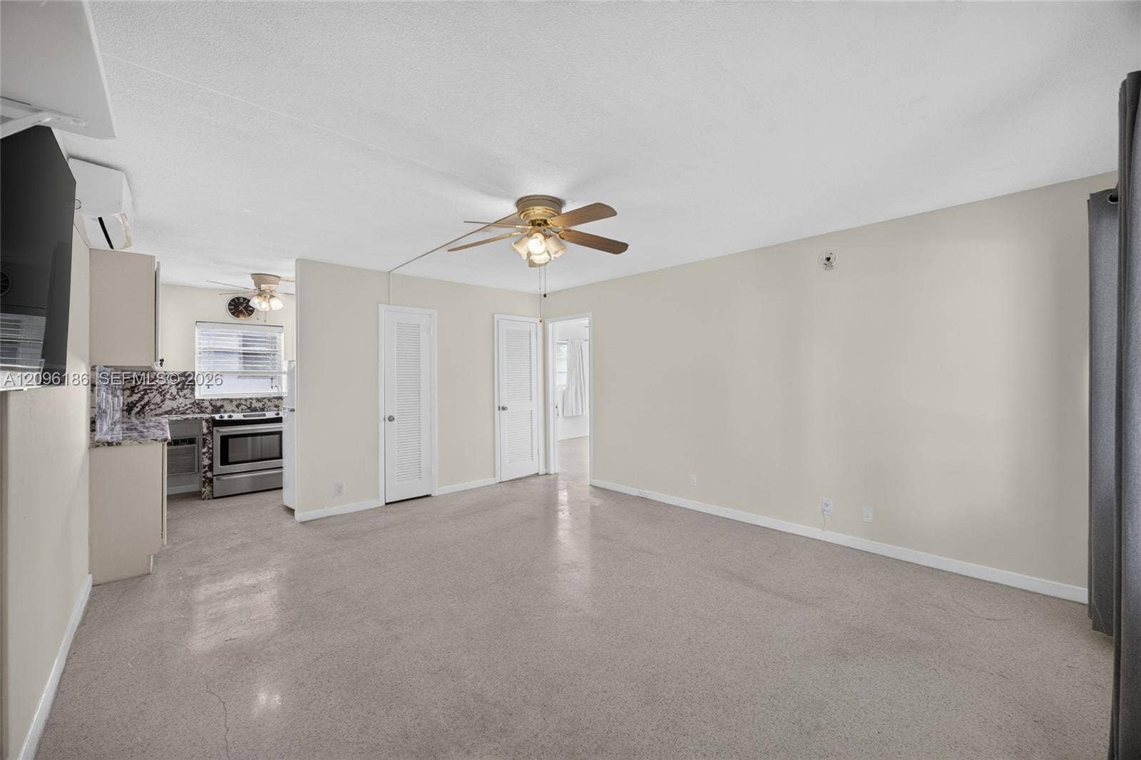 Interior space featuring polished concrete flooring, neutral wall tones, dual ceiling fans with integrated lighting, and louvered-style interior doors