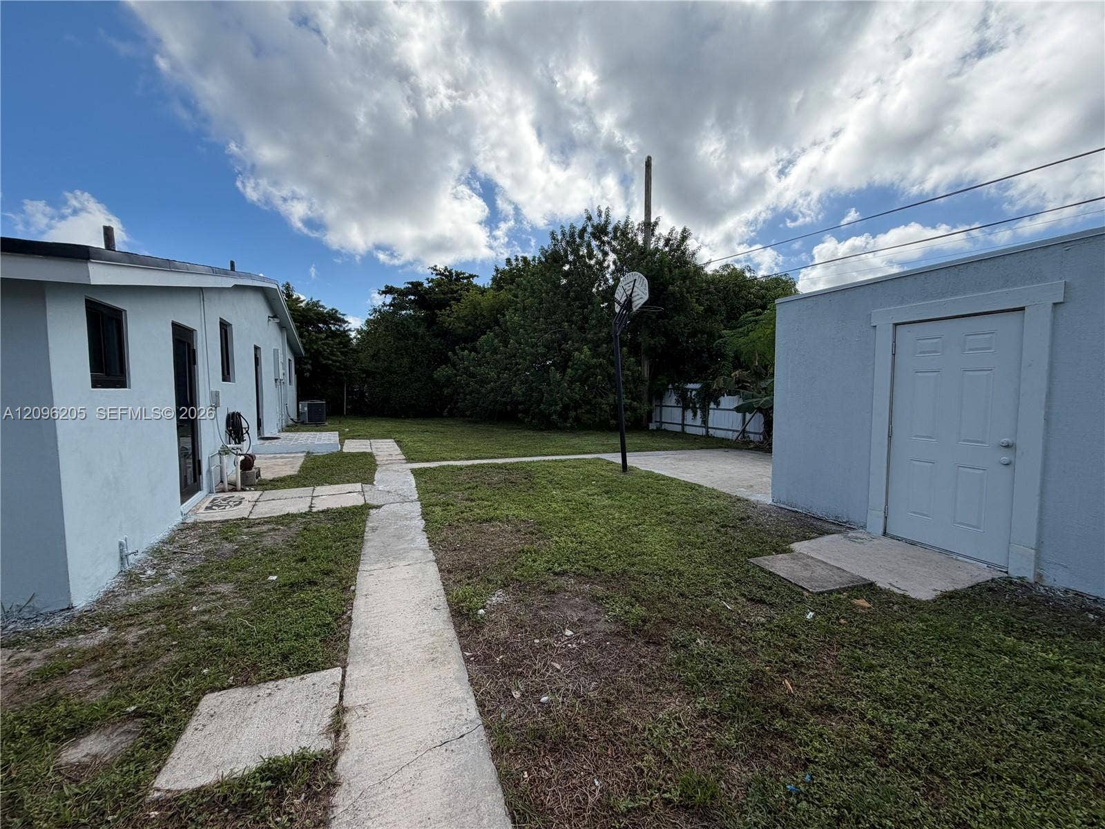 Backyard featuring a concrete walkway, detached storage structure, and lawn area