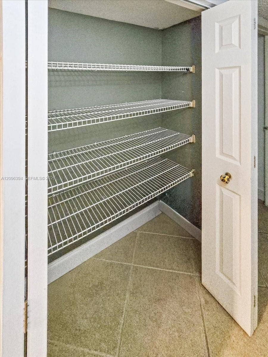 1830 Sabal Palm Drive, #105, Davie, FL 33324 Storage closet featuring four tiers of white wire shelving and tile flooring