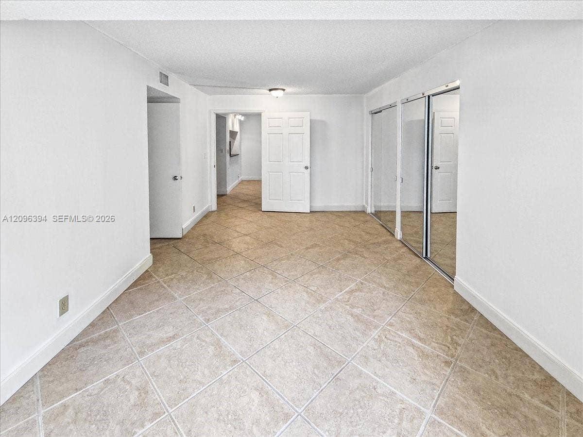 1830 Sabal Palm Drive, #105, Davie, FL 33324 Interior space featuring large-format tile flooring, dual mirrored sliding-door closets, and six-panel interior doors