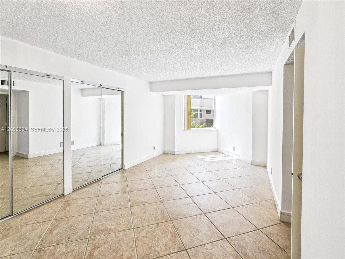 1830 Sabal Palm Drive, #105, Davie, FL 33324 Interior room featuring large-format tile flooring, wall-to-wall mirrored closet doors, and a window providing natural light
