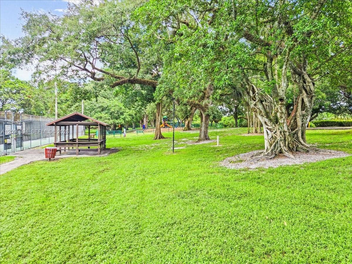 1830 Sabal Palm Drive, #105, Davie, FL 33324 Expansive green space featuring mature canopy trees, a covered wooden pavilion, and a fenced recreation court