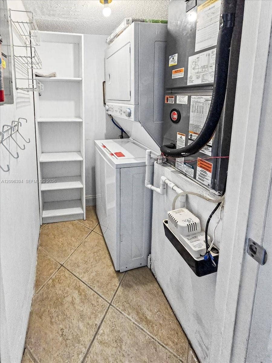 1830 Sabal Palm Drive, #105, Davie, FL 33324 Utility space featuring ceramic tile flooring, built-in shelving, stackable laundry units, and mechanical climate control system