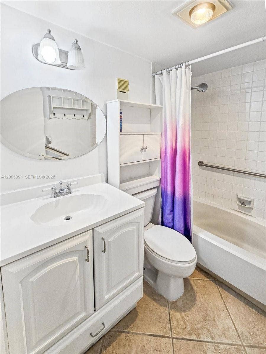 1830 Sabal Palm Drive, #105, Davie, FL 33324 White vanity cabinet with integrated basin, oval wall-mounted mirror, ceramic tile flooring, and tub-shower combination with tiled surround and metal grab bar