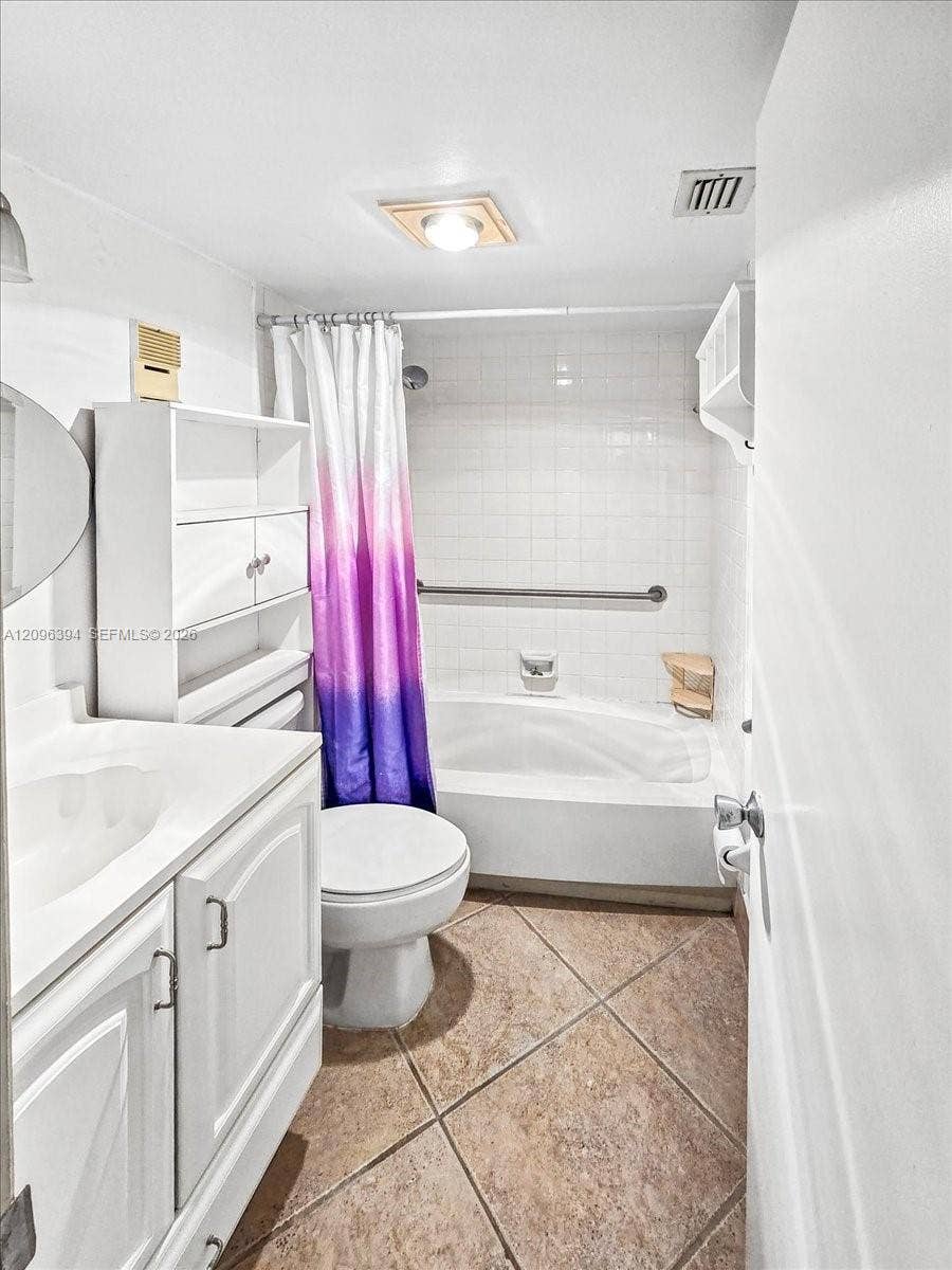 1830 Sabal Palm Drive, #105, Davie, FL 33324 Bathroom featuring tile flooring laid on a diagonal, a white vanity with integrated basin, built-in cabinetry, and a tub with tile surround and wall-mounted grab bar