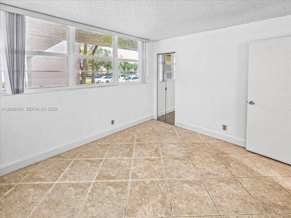1830 Sabal Palm Drive, #105, Davie, FL 33324 Neutral-toned tiled flooring, floor-to-ceiling windows, and a mirrored closet door