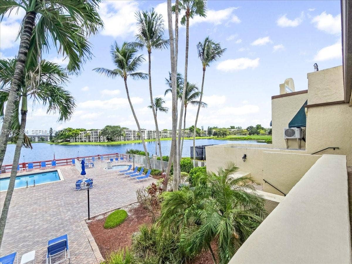 1830 Sabal Palm Drive, #105, Davie, FL 33324 Patio featuring stone-paver decking, swimming pool, in-ground spa, mature palm trees, and water frontage