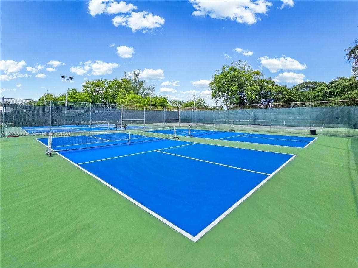 1830 Sabal Palm Drive, #105, Davie, FL 33324 Dual hard-surface courts featuring blue and green painted finishes, white boundary lines, integrated nets, and perimeter chain-link fencing with privacy screening