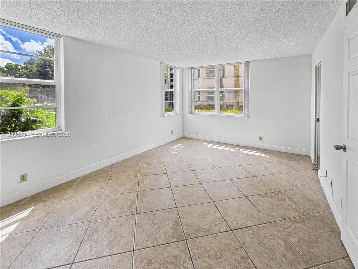 1830 Sabal Palm Drive, #105, Davie, FL 33324 Interior space featuring neutral-toned tile flooring, textured ceilings, and dual-aspect windows
