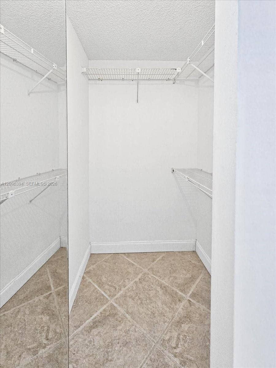 1830 Sabal Palm Drive, #105, Davie, FL 33324 Walk-in storage space featuring full-length mirror paneling, white wire shelving, and neutral ceramic tile flooring