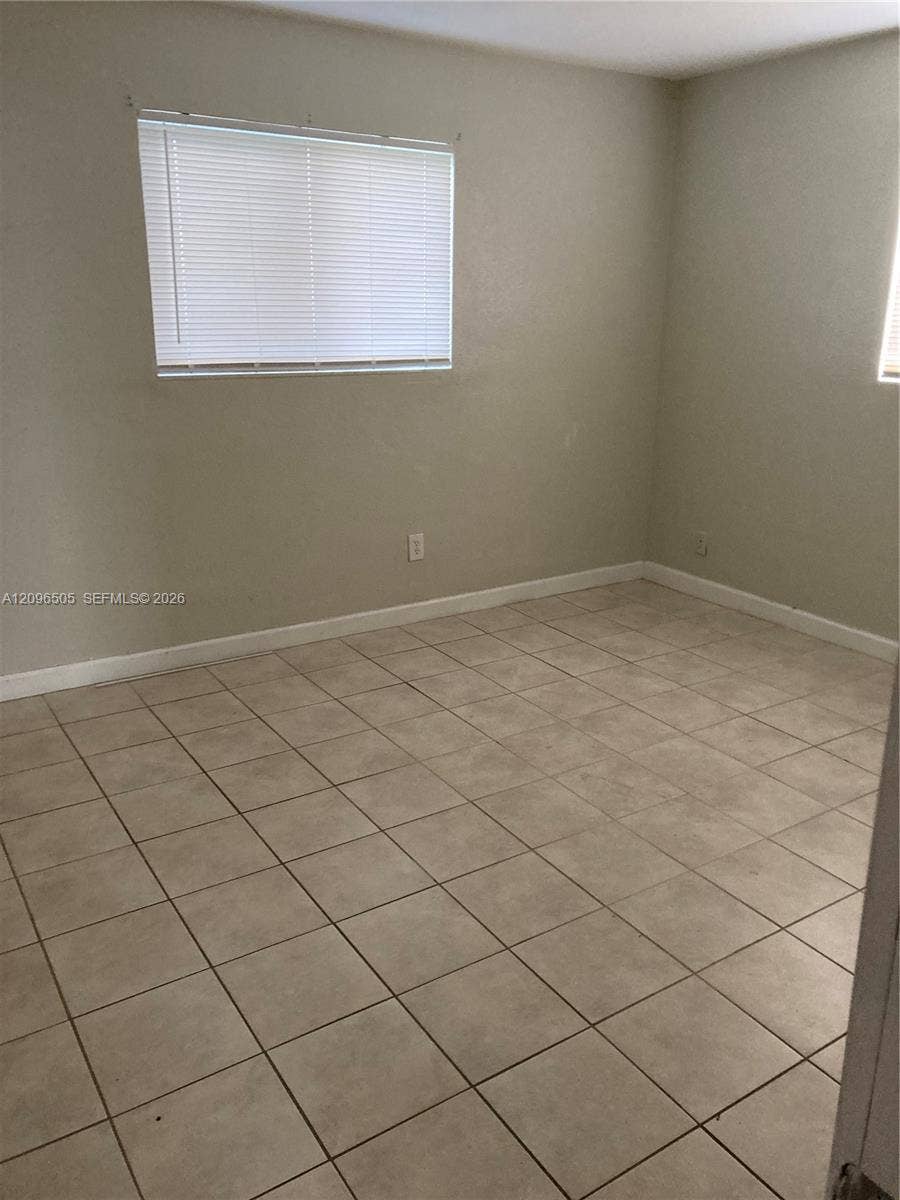 Neutral-toned room featuring ceramic tile flooring, neutral wall paint, and horizontal window blinds