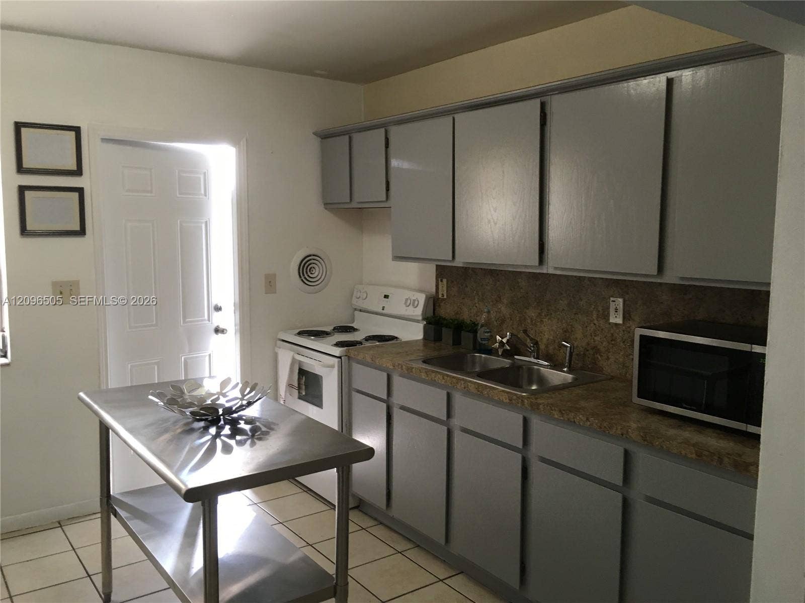 Kitchen featuring grey cabinetry, stone-finish countertops, dual-basin stainless steel sink, and ceramic tile flooring