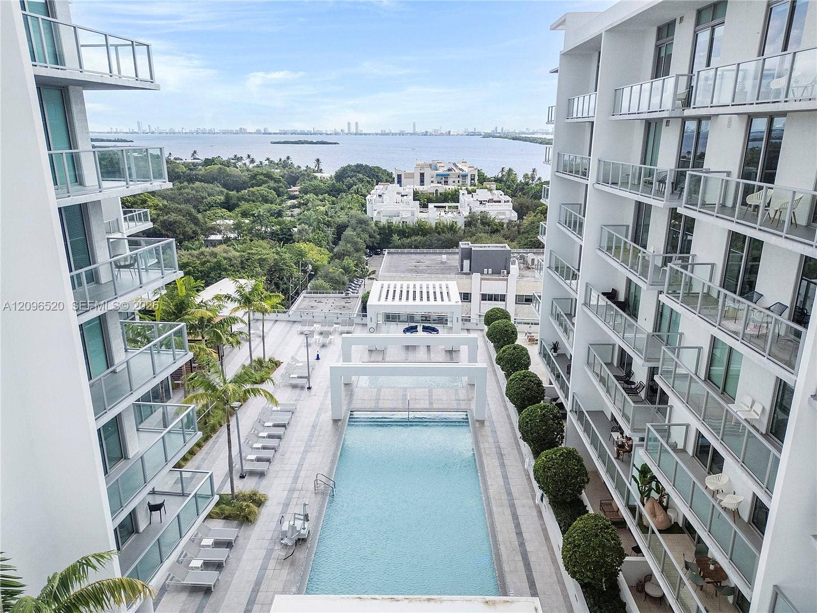 Modern architectural complex featuring private balconies with glass railings, an expansive outdoor swimming pool, stone-tiledjavascript:__doPostBack('m_ucDetailsView$m_btnCancel','') terrace, and manicured landscaping