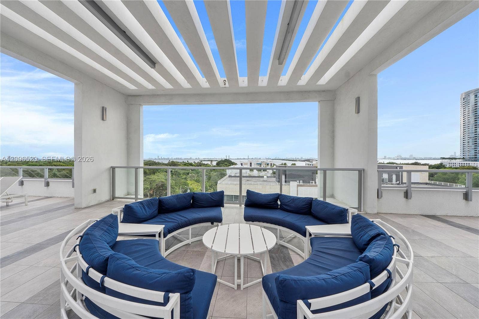 Covered rooftop terrace featuring a pergola-style ceiling, large-format tile flooring, and glass panel railings