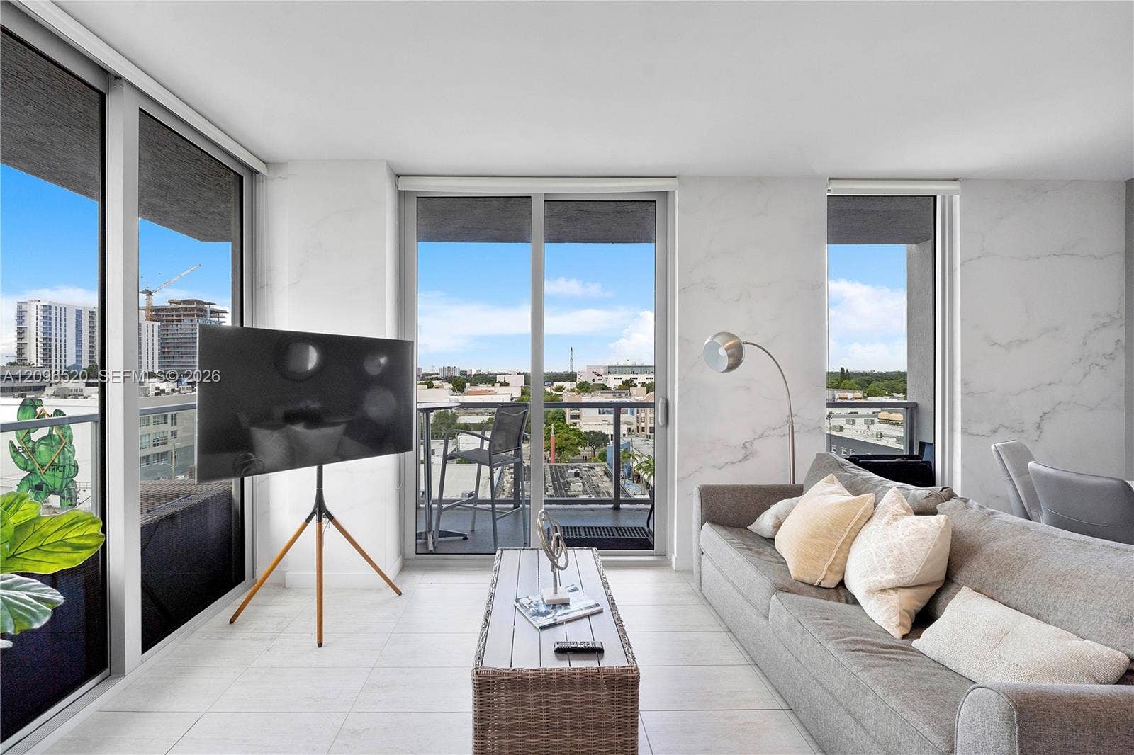 Living area featuring floor-to-ceiling glass sliding doors, stone-finish wall cladding, large-format tile flooring, and a private balcony with metal railing