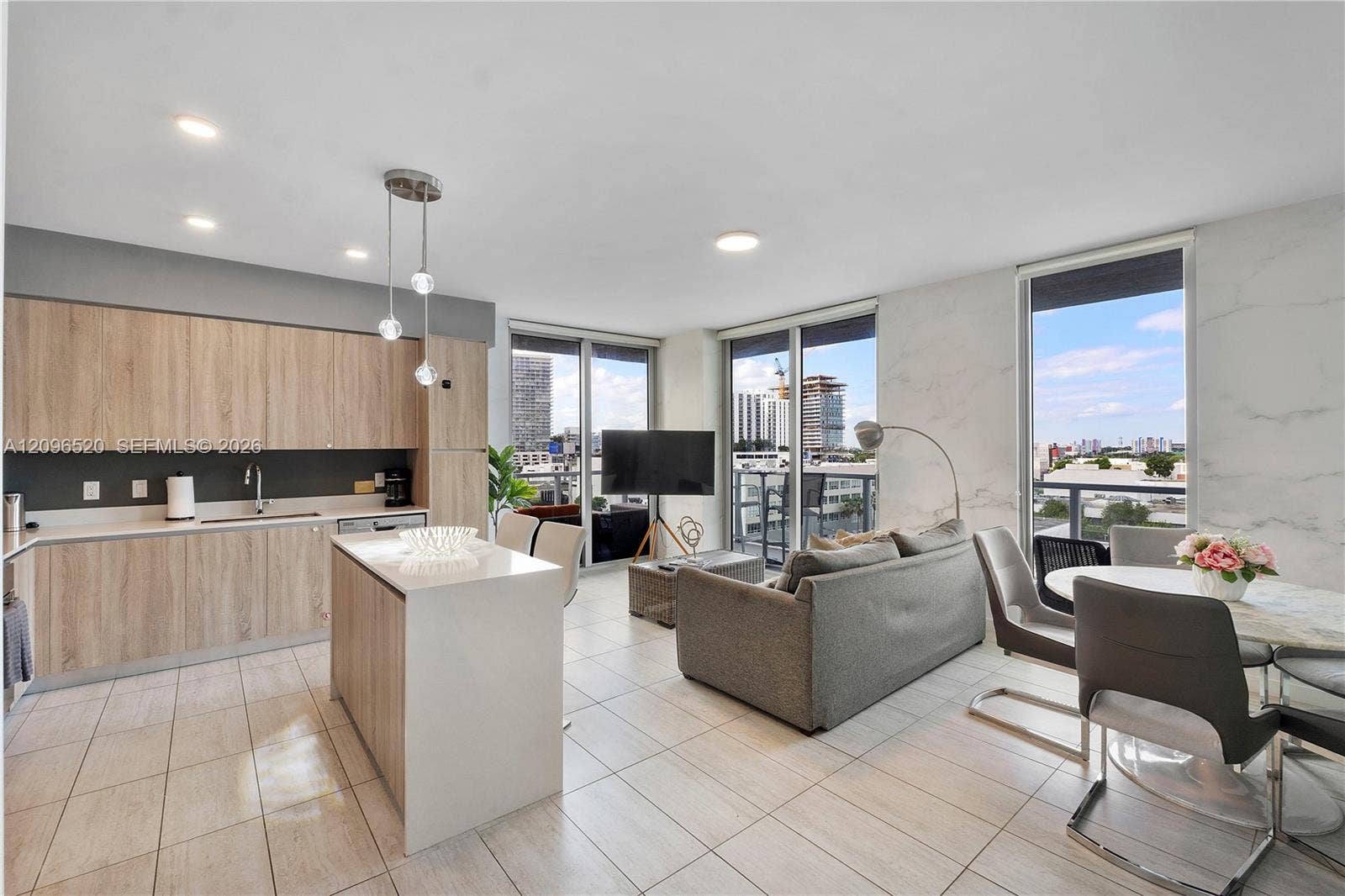 Kitchen featuring wood-finish cabinetry, a central island with a solid-surface countertop, floor-to-ceiling windows, and tile flooring