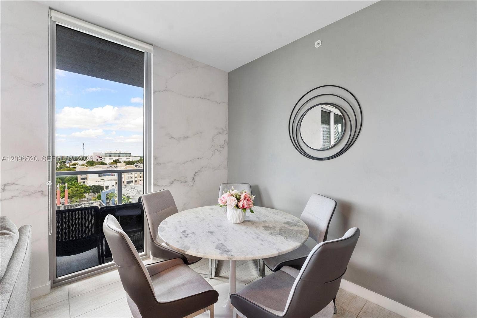 Floor-to-ceiling glass door with integrated balcony, stone-finish wall cladding, and large-format tile flooring