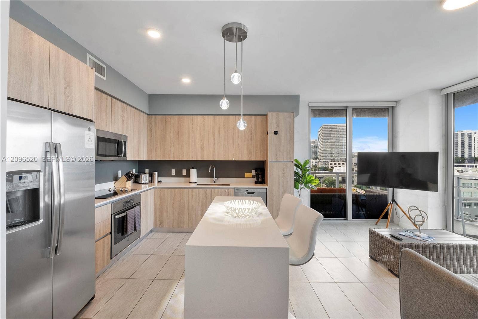 Kitchen featuring light-finish cabinetry, a central island with a solid-surface countertop, stainless steel appliances, modern pendant lighting, and ceramic tile flooring