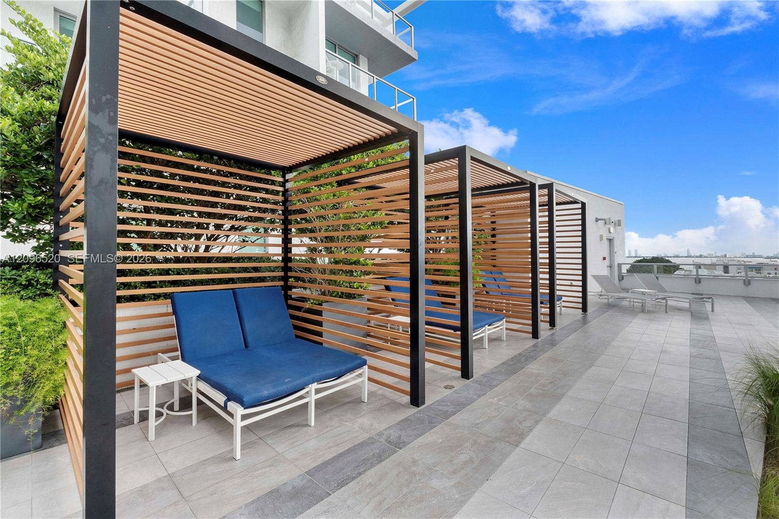 Rooftop terrace featuring built-in wood-slat privacy cabanas, black metal framing, large-format tile flooring, and integrated landscaping