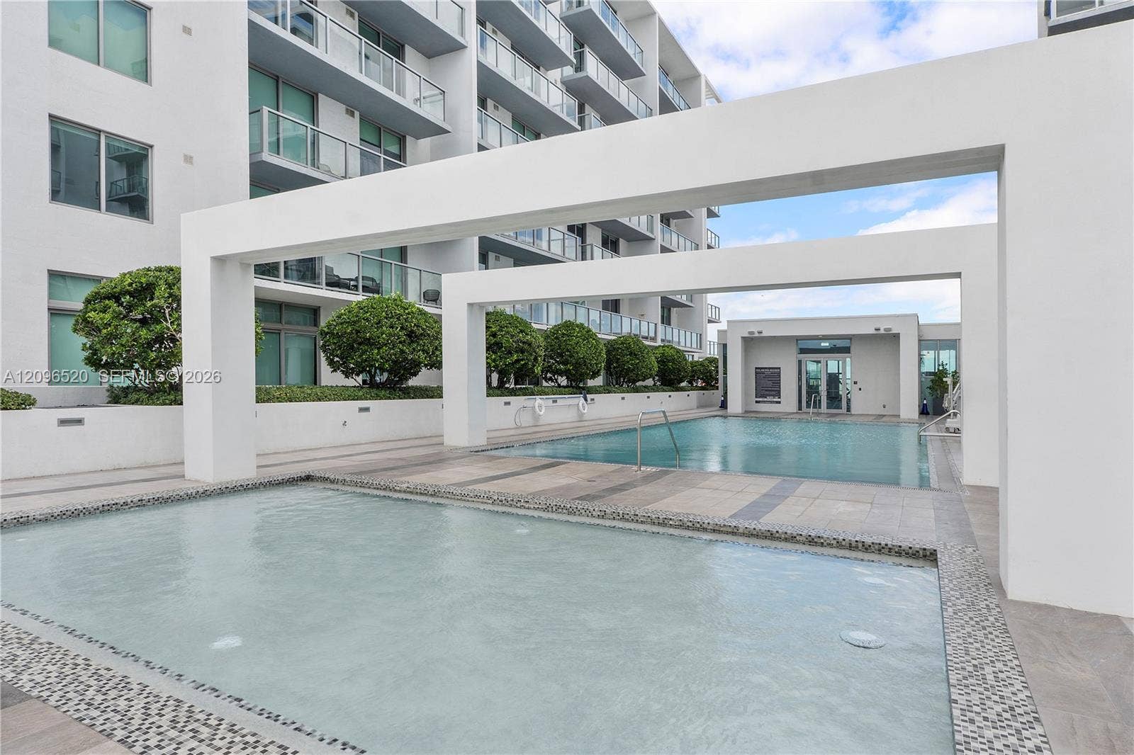 Multi-level pool area featuring built-in architectural pergolas, tiled decking, and tiered water features
